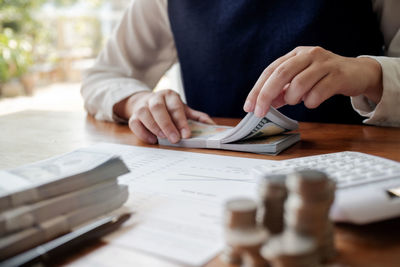 Midsection of woman holding paper with text on table