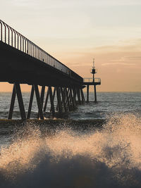 Pier over sea against sky during sunset