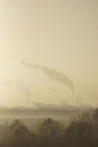 Smoke emitting from factory against clear sky