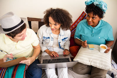 Friends using laptop while sitting at home