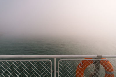 Fence by sea against sky