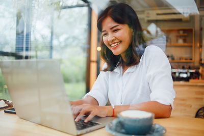 Smiling businesswoman using technology at cafe