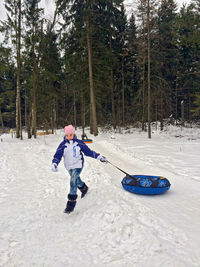 Full length of teenage girl pulling inflatable ring on snow