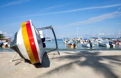 Sailboats moored on beach against sky