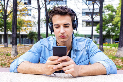 Man listening music while using mobile phone in city