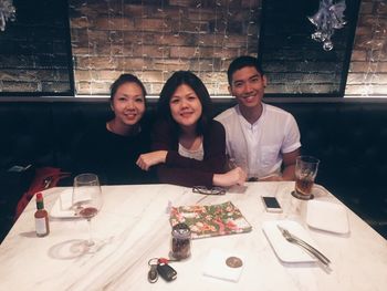 Portrait of happy friends sitting on table