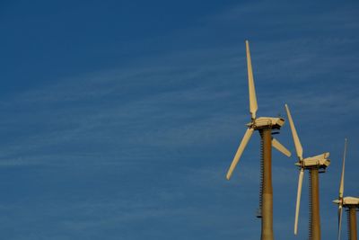 Low angle view of wind turbine against blue sky