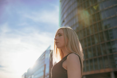 Low angle view of young woman looking away in city