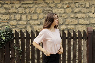 Young woman standing against wall