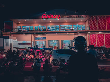 Rear view of people walking on illuminated road at night