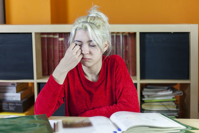 Young woman sleeping while studying in library