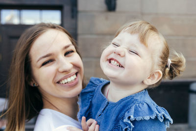 Portrait of smiling mother with daughter outdoors