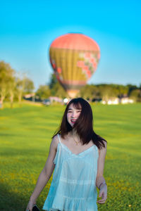 Portrait of young woman with balloons against sky