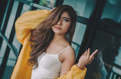 Portrait of beautiful woman standing against yellow wall