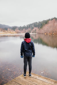 Rear view of man standing by lake against sky