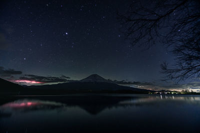 Scenic view of lake and mountains against sky at night