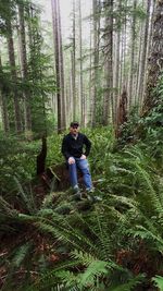Man standing on tree trunk in forest