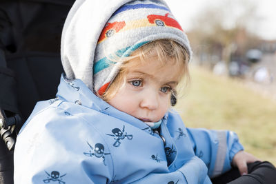 Cute baby girl sitting in stroller outdoors