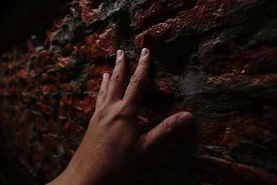 Close-up of hand touching brick wall 