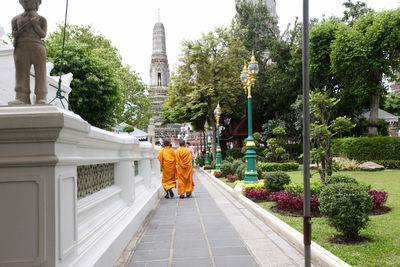 Rear view of monks walking on footpath at temple