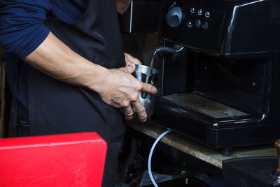 Midsection of man preparing coffee at table