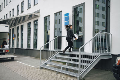 Full length of man standing on railing against buildings in city