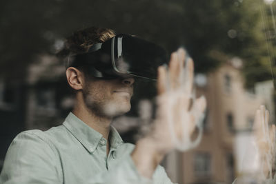 Young man standing at the window, using vr glasses