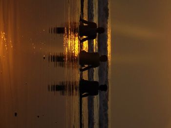 Silhouette people at home against sky during sunset