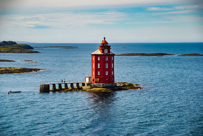 Lighthouse by sea against sky