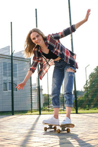 Full length portrait of smiling young woman standing against sky