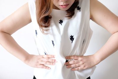 Midsection of woman standing by white wall