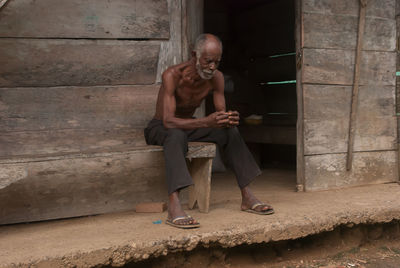 Full length of man sitting against wall