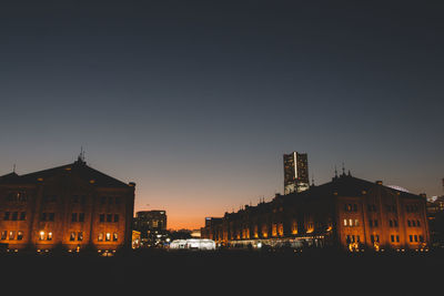 Illuminated cityscape against clear sky at night