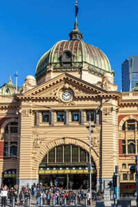 Group of people in front of building against blue sky