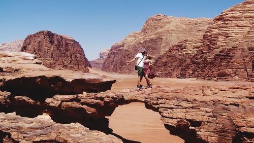 People on rock formation against sky