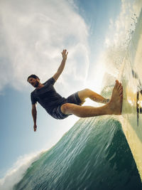 Tilt image of man surfing on sea against sky