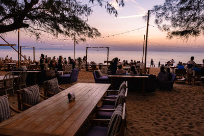 People at beach against sky during sunset