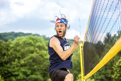 Low angle view of man playing volleyball against trees