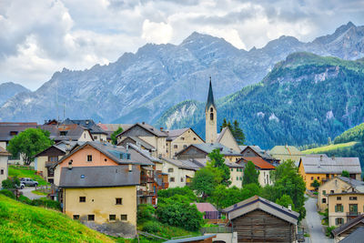 Town by buildings and mountains against sky