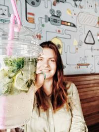 Portrait of smiling young woman holding lemonade in restaurant