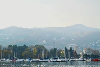 Sailboats in sea by city against sky