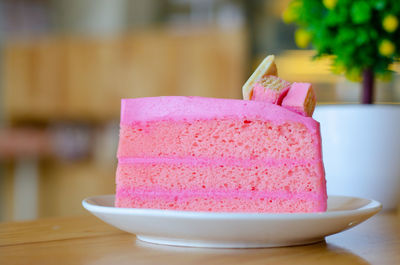 Pink cake on white disk with wood table, holiday time.