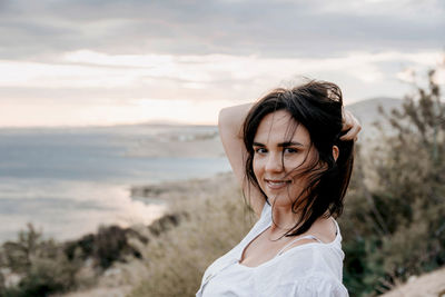 Portrait of smiling woman standing on land against sky