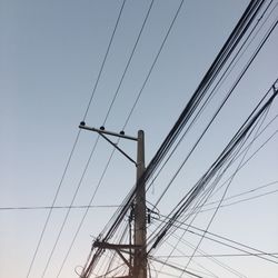 Low angle view of electricity pylon against clear sky