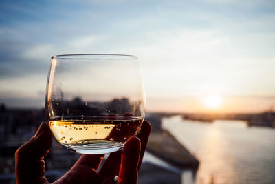 Close-up of hand holding wine against sky