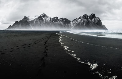 Scenic view of sea by snowcapped mountains against sky