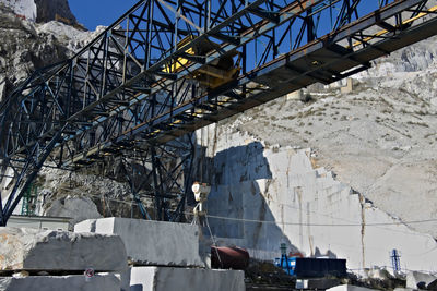 Low angle view of bridge by buildings against sky