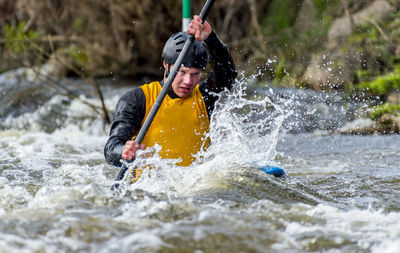 Portrait of man splashing water in river