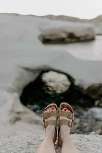 Low section of woman standing on sand at beach