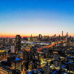 Aerial view of illuminated city buildings against clear sky